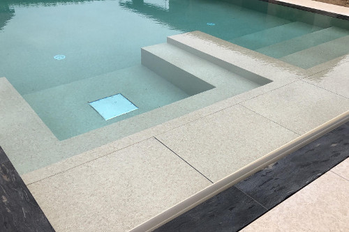 Area relax  con bubble jet e carabottino copertura tapparella immerso con rivestimento in PVC Touch sublime in piscina realizzata da Acqua SPA