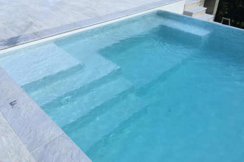 scala di ingresso ed area relax in piscina con cascata infinity